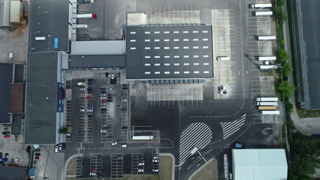 Top-down-aerial-view-of-car-parking-space-in-Riga-city-with-cars-and-large-trucks-parked-in-formation,-Latvia