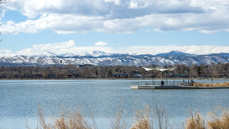 Time-lapse-of-a-public-dock-in-the-middle-of-Sloan-Lake-in-Denver,-Colorado-with-blurred-people-passing-in-the-foreground