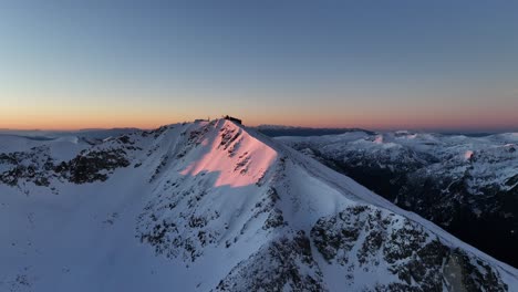 Drone-shot-of-Musala-peak-during-sunrise,-dawn,-Bulgaria,-Rila-mountain,-highest-summit-on-the-Balkans,-clear-weather,-clear-sky,-amazing,-stunning-view,-sunny-slopes,-golden-hour,-blue-hour