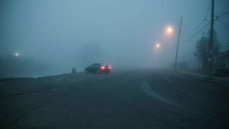 Auto-In-Leerer-Straße-Geparkt,-Während-Der-Dämmerung-Mit-Nebel-Bedeckt,-Mit-Schlecht-Sichtbaren,-Leuchtenden-Straßenlaternen-4k