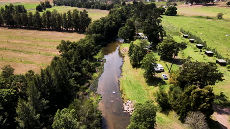 Descending-drone-shot-over-rural-campsite---people-floating-down-river