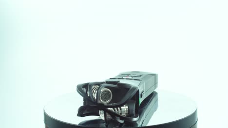 A-close-up-shot-of-a-handy-pocket-audio-recorder,-black-sound-stereophone,-on-a-reflecting-360-rotating-stand,-line-in-and-out-port,-volume-buttons,-slow-motion,-4K-video