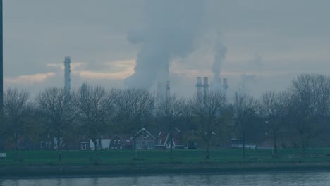 Ein-Vorort-In-Rotterdam-Mit-Einem-Industriegebiet-Im-Hintergrund,-In-Dem-Rauch-Von-Türmen-Aufsteigt