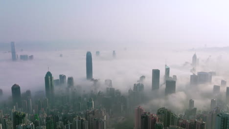 Cinematic-shot-of-Mystical-morning-fog-covering-city-of-Hong-Kong-with-high-rise-buildings-over-the-clouds