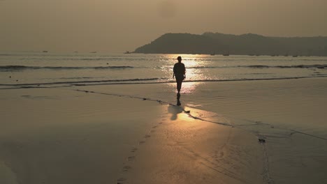 Landschaftsansicht-Einer-Jungen-Frau,-Die-Bei-Sonnenuntergang-An-Einem-Sandstrand-Am-Meer-Spazieren-Geht