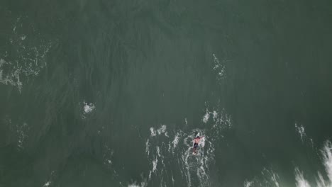 Drone-top-view,-two-surfers-passing-waves