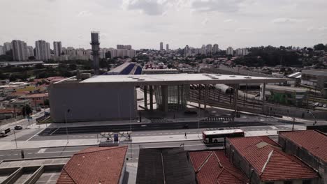 Orbital-from-left-to-right-in-front-of-Vila-Sônia-subway-station-in-São-paulo,-Brazil-with-a-background-with-a-lot-a-buildings-in-a-bright-day