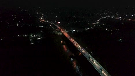 4k-Drone-video-of-vehicles-passing-on-a-bridge-over-a-river-at-night