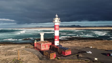 Aerial-View-Of-El-Toston-Lighthouse-And-Faro-El-Cotillo-Museum-With-Atlantic-Ocean-Waves-In-The-Background