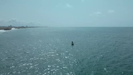 Victoria-Island-Lagos,-Nigeria---20-November-2022:-Drone-view-of-a-fisherman-on-a-fishing-boat-on-the-coastline-of-Lagos