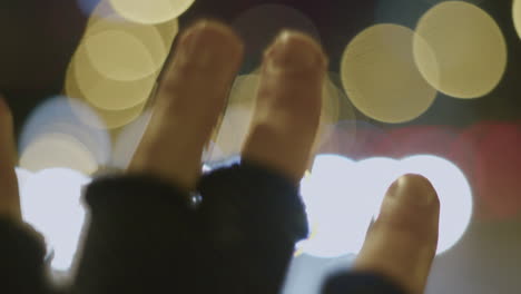 Closeup-of-Hand-in-Gloves-with-Bokeh-of-Blurry-Traffic-Lights-at-Night