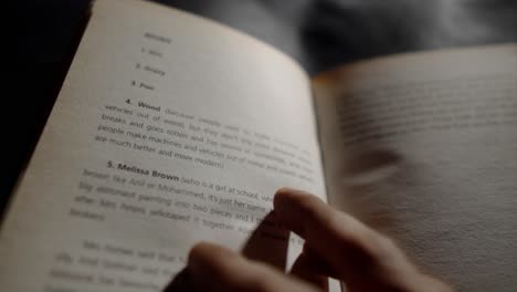 close-up-of-a-hand-turning-the-page-of-a-book-with-text-on-the-pages-in-focus,-and-the-words-clearly-legible