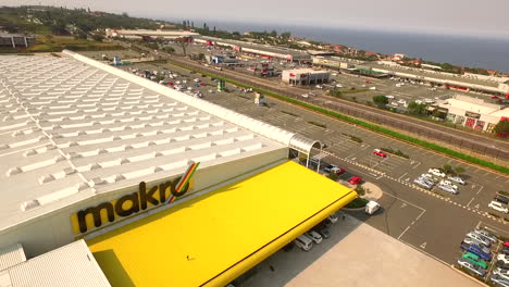 Aerial-drone-Shot-of-Makro-Shopping-Centre-with-the-ocean-in-background