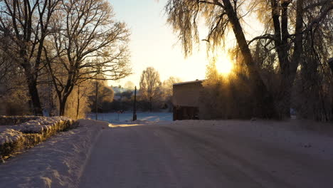 Snow-and-ice-covered-road-on-sunny-winter-morning-on-golden-hour,-dolly-in