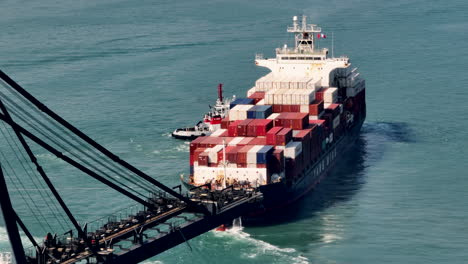 Tug-Boat-Pulling-Container-Ship-Out-to-Sea,-Aerial-Shot