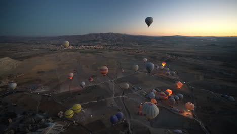Heißluftballons-Und-Kappadokische-Landschaft-Im-Morgengrauen,-Fliegende-Fallschirme-Und-Brennerflammen,-Luftaufnahme-Des-Heißluftballonkorbs
