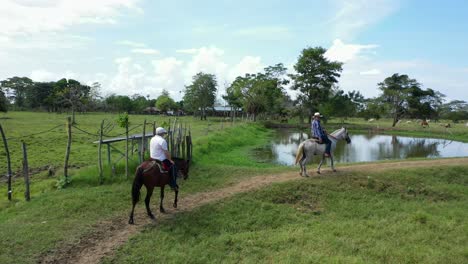 Aerial-shot-of-men-riding-horses-in-a-beautiful-farm