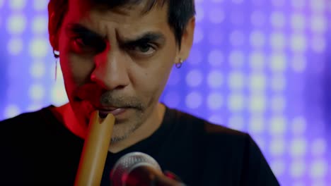 Close-Up-Shot-Of-Musician-Playing-Recorder,-Blurry-Colorful-Lights-In-Background