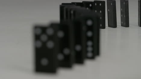 row-of-black-dominoes-with-white-spots-falling-in-studio