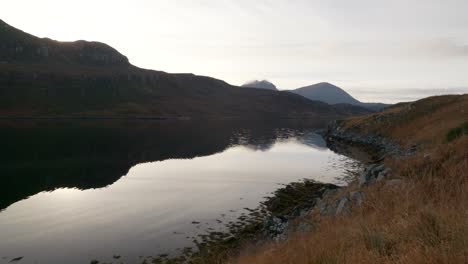 gentle-ripples-move-across-the-surface-of-still-water-in-a-sea-loch-in-Scotland-as-the-sun-sets-behind-mountains-