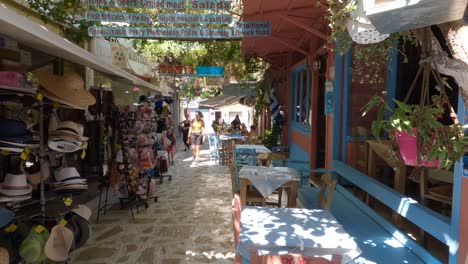 People-walking-along-touristic-narrow-street-with-restaurants-and-Souvenir-shops-in-Preveza,-Greece