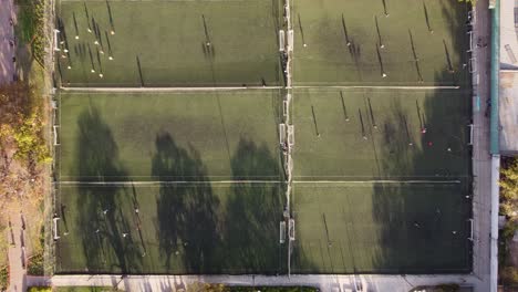 Eine-Stationäre-Luftaufnahme-Von-Oben-Nach-Unten-Von-Fußballspielern,-Die-Gleichzeitig-Auf-Sechs-Angrenzenden-Fußballfeldern-Fußball-Spielen