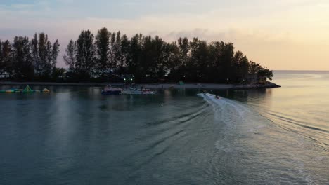 Sonnenuntergang-Luftaufnahme-Mit-Bananenbootfahrt-Zurück-Zum-Ufer-Im-Paradies-101,-Lustige-Aufblasbare-Wasseraktivität-In-Langkawi,-Kedah,-Malaysia,-Südostasien
