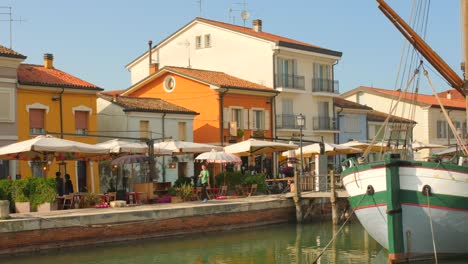 Waterfront-Restaurants-With-Boat-Docked-At-Daytime-On-Canal-Port-Of-Cesenatico-In-Italy