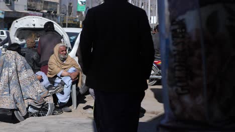 Gruppe-Von-Einheimischen,-Die-Auf-Stühlen-Am-Straßenrand-Sitzen,-Während-Der-Verkehr-In-Quetta,-Pakistan,-Vorbeifährt