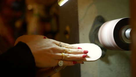 Female-shoemaker-polishing-leather-sole-close-up-on-industrial-workshop-machine