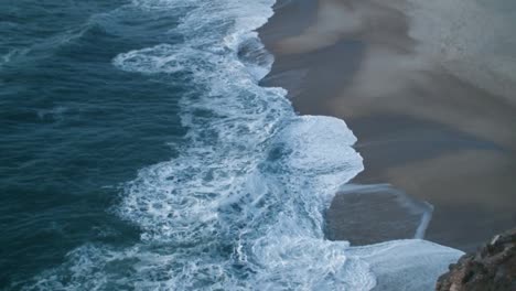 Große-Wellen-Brechen-An-Der-Küste-Von-Nazare-In-Portugal,-Aufgenommen-Von-Oben-An-Einem-Spätsommernachmittag