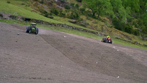 Trackers-plowing-the-fields-on-a-steep-mountain-while-birds-are-flying-by