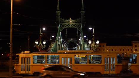 Nightlife,-Cityscape-with-a-Bridge,-a-Bus-and-a-Tram-Crossing-the-Road-at-Budapest