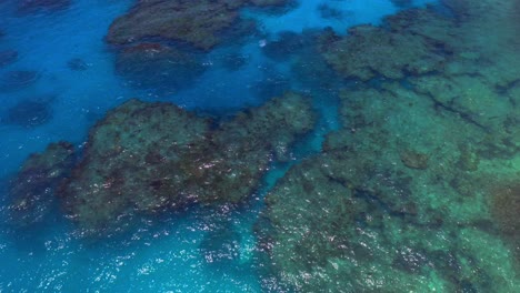 A-bird's-eye-view-provided-by-the-drone,-shows-the-Blue-lagoon's-mesmerizing-transparency-revealing-the-hidden-beauty-of-rocks-and-sea-life