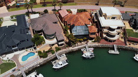 Aerial-view-of-luxury-townhouses-by-the-sea,-with-private-dock-for-boats