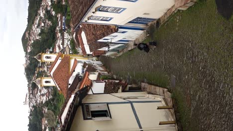 traveler-walks-down-narrow-cobbled-slope-between-historic-buildings-in-Ouro-Preto,-MG,-Brazil