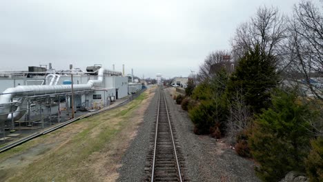 Reverse-Aerial-on-of-Train-track-with-Factory-in-shot-in-kernsville-nc