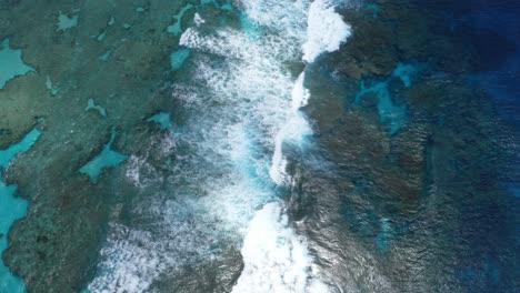 The-drone's-shot-captures-the-blue-lagoon-in-all-its-glory,-showcasing-the-clear-waters-that-reveal-the-beauty-of-the-rocks-below,-as-the-waves-crash-on-the-reef-adding-a-sense-of-natural-beauty