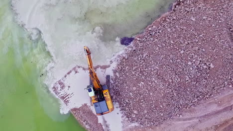 Birdseye-view-areal-shot-of-a-industrial-loader-digging-for-sand-in-the-ocean-and-putting-on-the-beach