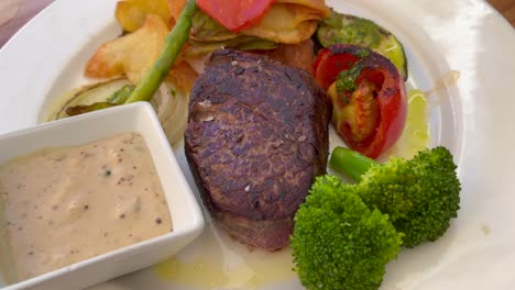 Juicy-sirloin-fillet-steak-with-peppercorn-sauce,-vegetables-and-potatoes-at-a-restaurant,-delicious-high-quality-beef,-4K-shot