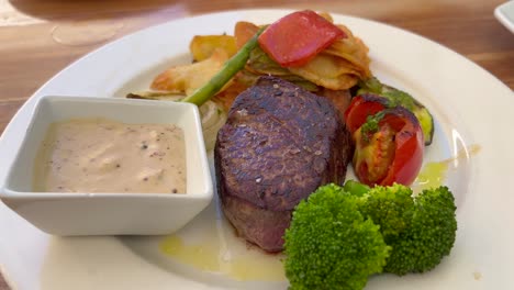 Juicy-sirloin-fillet-steak-with-peppercorn-sauce,-vegetables-and-potatoes-at-a-restaurant,-high-quality-beef,-4K-shot