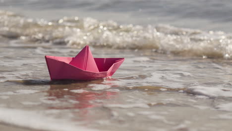 Die-Hand-Der-Frau-Legt-Ein-Origami-Boot-Ins-Meer-Und-Es-Schwimmt-Davon