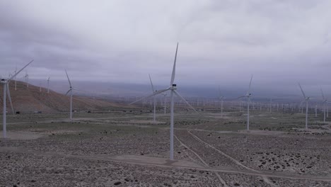 Aerial-footage-of-a-wind-farm-in-the-Palm-Springs-desert-on-a-cloudy-day,-fast-zoom-in