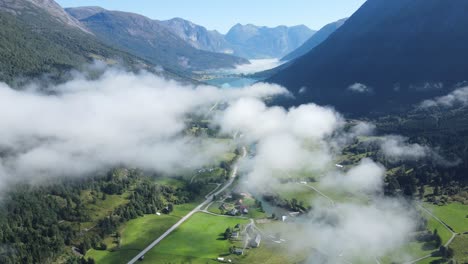 Flying-over-valley-with-glacier-lake-down-there,-mist-and-high-mountains-o