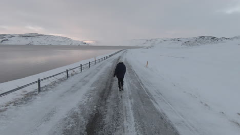 Girl-walking-on-slippery-frozen-road,-Westfjords