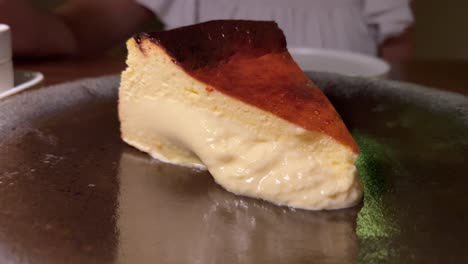 Traditional-Spanish-burnt-basque-cheesecake,-sweet-creamy-dessert-on-a-plate-in-a-restaurant,-4K-shot