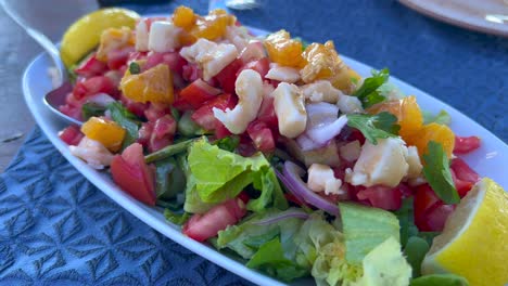 Delicious-and-healthy-salad-with-feta-cheese,-tomatoes,-lettuce,-onion,-orange-and-lemons,-tasty-lunch,-4K-shot