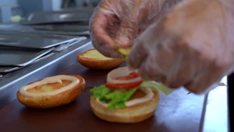 Der-Koch-Bereitet-Burger-Sandwiches-Zu-Und-Legt-Gemüse-Aufs-Brot