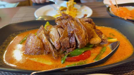 Traditional-crispy-duck-in-spicy-red-curry-sauce-with-vegetables,-authentic-Thai-cuisine-restaurant,-4K-shot