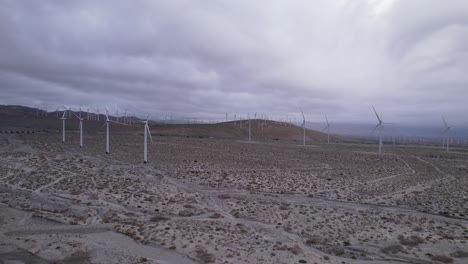 Aerial-shot-showcasing-a-wind-farm-in-the-desert-region-of-Palm-Springs-during-a-cloudy-day,-forward-dolly